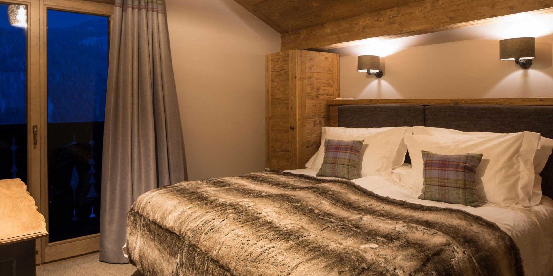 Chalet Les Clarines Chatel Les Portes du Soleil Frankrijk wintersport skivakantie luxe slaapkamer 2-persoonsbed sprei kussens wandlampen houten balken raam balkon bergen bomen
