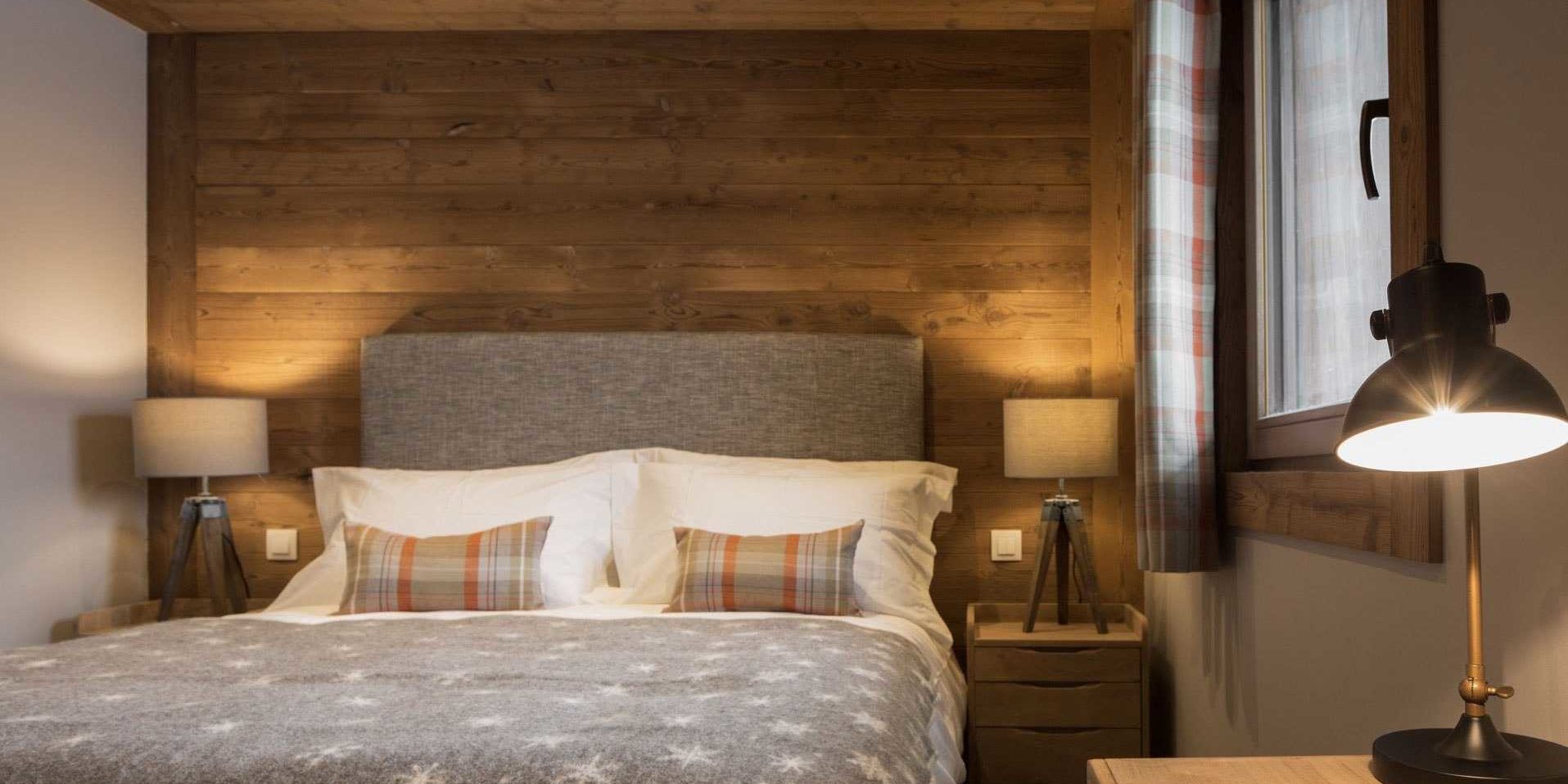 Chalet Les Clarines Chatel Les Portes du Soleil Frankrijk wintersport skivakantie luxe slaapkamer 2-persoonsbed sprei grijs hoofdbord kussens nachtlampjes houten wand raam