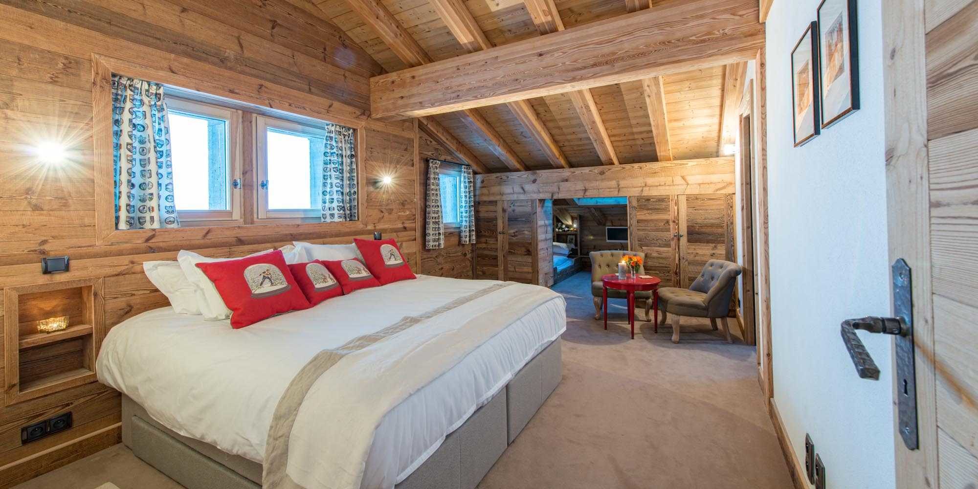 Chaletneuf du Tenne Chatel Les Portes du Soleil Frankrijk wintersport skivakantie luxe slaapkamer 2-persoonsbed rode kussens rood tafeltje fauteuils ramen 1-persoonsbed TV kindergedeelte houten wanden houten balken 3-persoonskamer