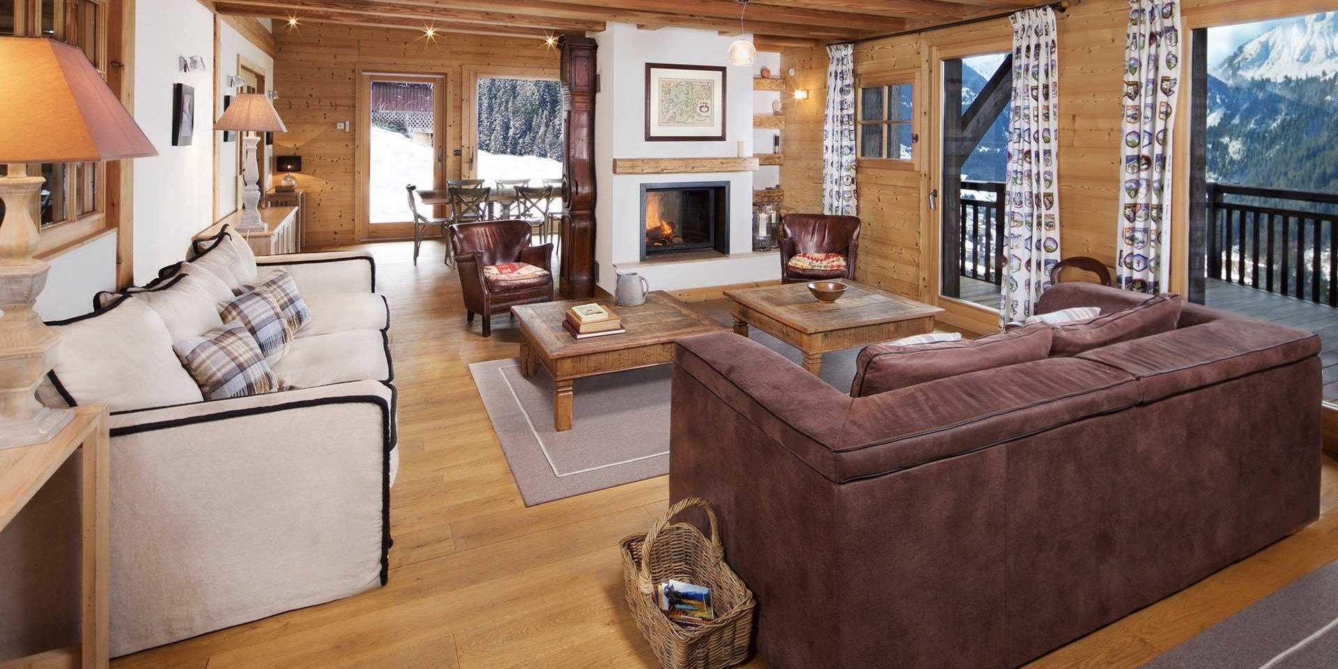 Chaletneuf du Tenne Chatel Les Portes du Soleil Frankrijk wintersport skivakantie luxe living bruine bank witte bank salontafels bruine fauteuils open haard schilderij vloerkleed mandje eetkamer hoge ramen balkon bergen bomen sneeuw