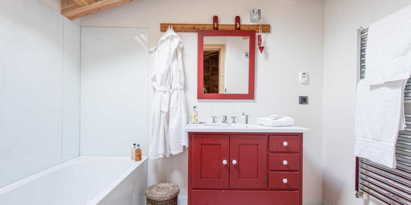 Chaletneuf du Tenne Chatel Les Portes du Soleil Frankrijk wintersport skivakantie luxe rode badkamer bad wastafel spiegel handdoekenrek badjas houten balken mand