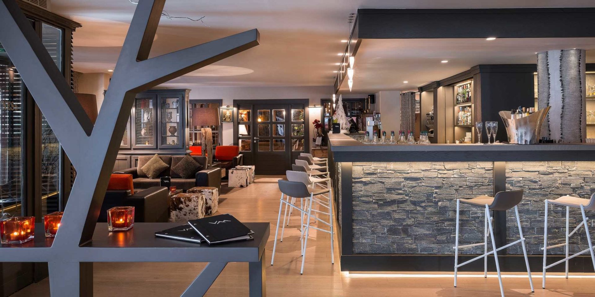 Hotel Village Montana Tignes Tignes-Val d'Isere Frankrijk wintersport skivakantie luxe bar barkrukken kaarsen kunst lounge zwarte banken gekleurde kussens hockers dranken