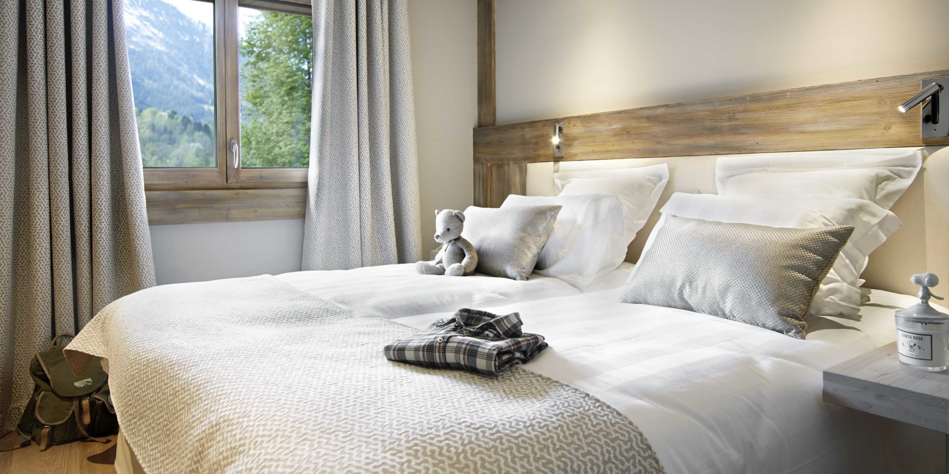 MGM Residence Les Chalets Elena Les Houches Chamonix Mont Blanc Frankrijk wintersport skivakantie luxe slaapkamer 2-persoonsbed sprei beertje pyjama tas nachtlampjes raam bomen bergen sneeuw