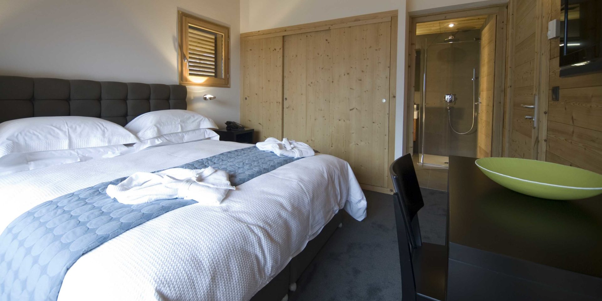 Maison Blanche et Verte Chatel Les Portes du Soleil Frankrijk wintersport skivakantie luxe slaapkamer hoofdbord sprei houten wandkast bureau stoel groene schaal badkamer douche vloerbedekking