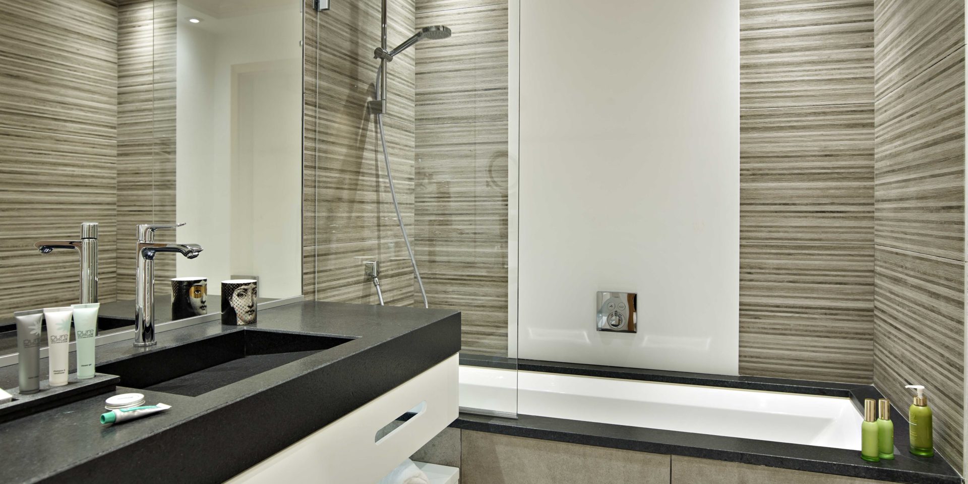 MGM Residence Alexane Samoens Le Grand Massif Frankrijk wintersport skivakantie luxe badkamer bad grijs gestreepte tegels wastafel spiegel badproducten