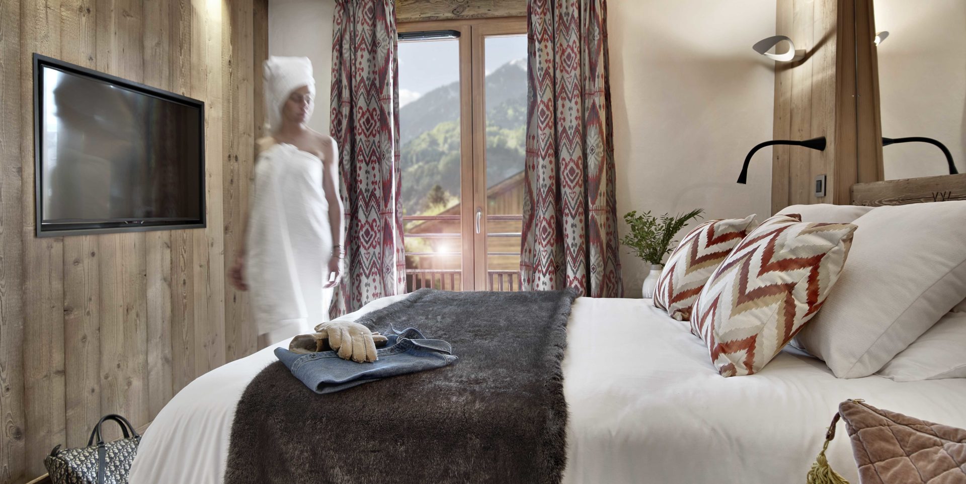 MGM Residence Alexane Samoens Le Grand Massif Frankrijk wintersport skivakantie luxe slaapkamer 2-persoonsbed rood witte kussens TV tas dame handdoeken raam balkon bergen