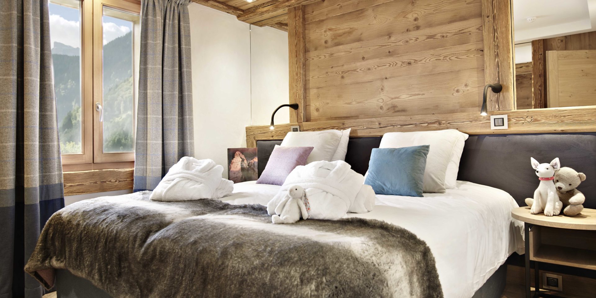 MGM Residence Alexane Samoens Le Grand Massif Frankrijk wintersport skivakantie luxe slaapkamer 2-persoonsbed badjassen knuffels paars blauw kussen raam houten achterwand