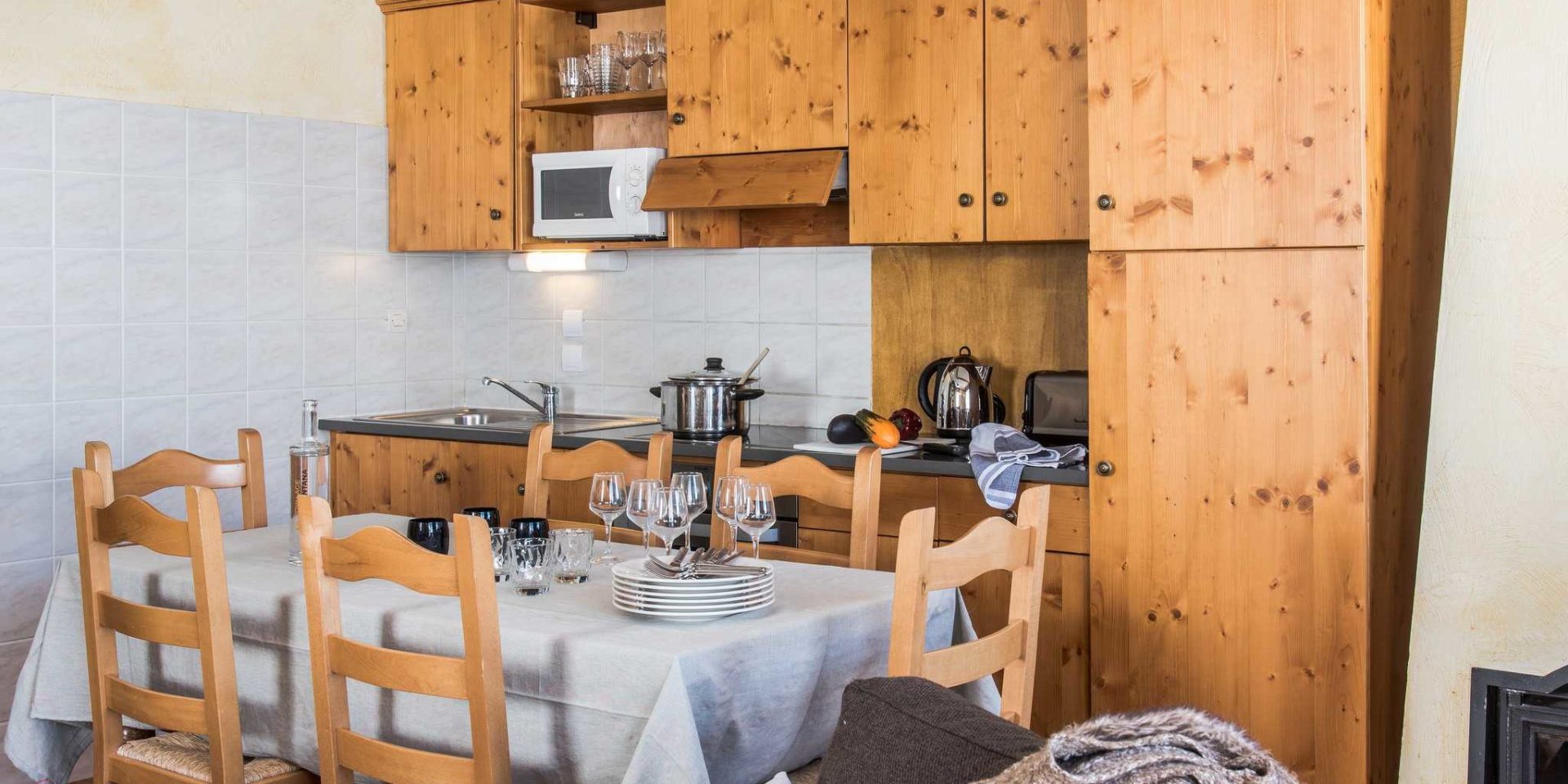 Residences Village Montana Tignes Tignes-Val d'Isere Frankrijk wintersport skivakantie luxe keuken 5K8 eettafel wijnglazen houten stoelen houten kastjes kookplaat pan waterkoker