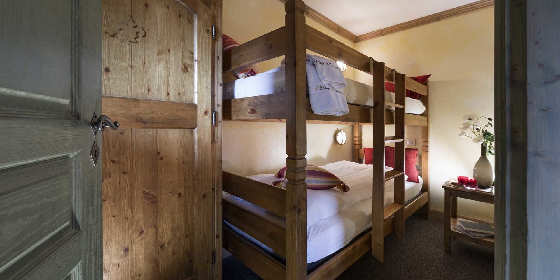 Residences Village Montana Tignes Tignes-Val d'Isere Frankrijk wintersport skivakantie luxe kinderslaapkamer stapelbed trap rode kussens handdoeken tafeltje vaas rode kaarsen