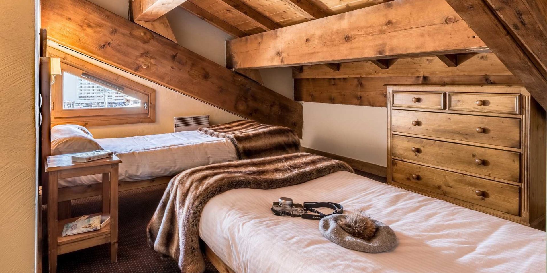 Residences Village Montana Tignes Tignes-Val d'Isere Frankrijk wintersport skivakantie luxe slaapkamer aparte bedden sprei fototoestel tafeltje boek kast raam houten balken