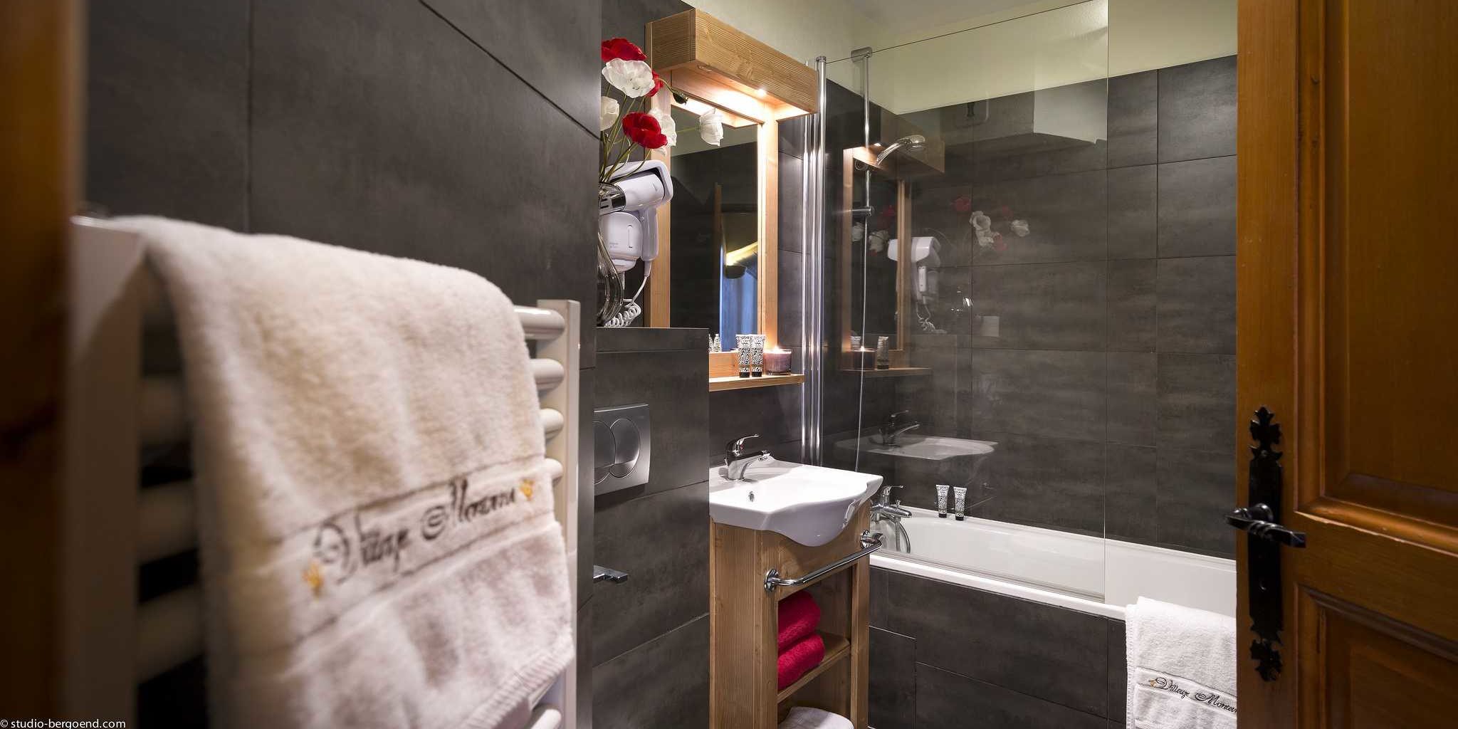 Residences Village Montana Val Thorens Les 3 Vallees Frankrijk wintersport skivakantie luxe badkamer bad wastafel spiegel handdoekenrek handdoeken Village Montana bloemen fohn grijze tegels