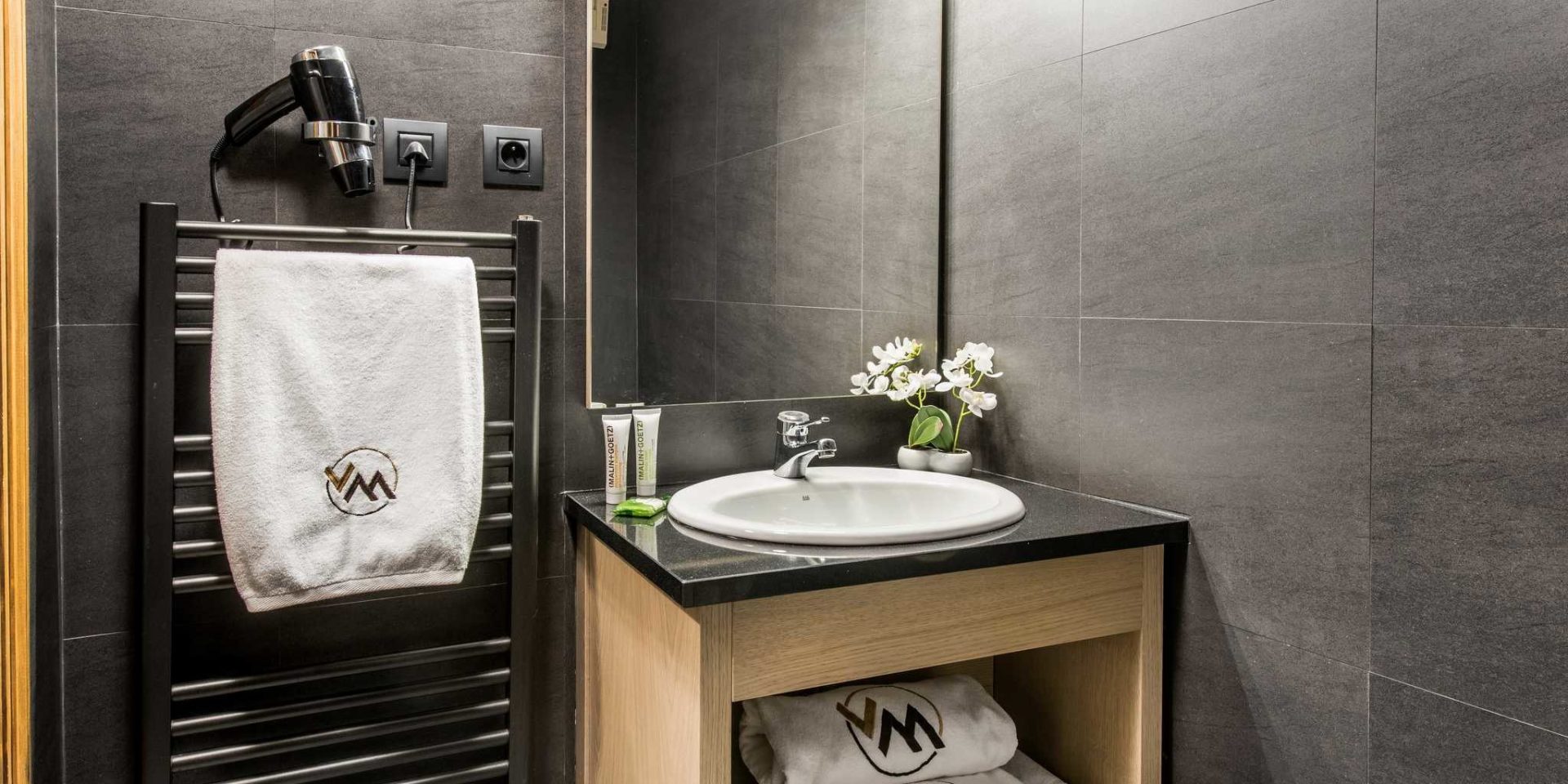 Residences Village Montana Val Thorens Les 3 Vallees Frankrijk wintersport skivakantie luxe badkamer wastafel spiegel handdoekenrek handdoekenVM Orchidee fohn grijze tegels