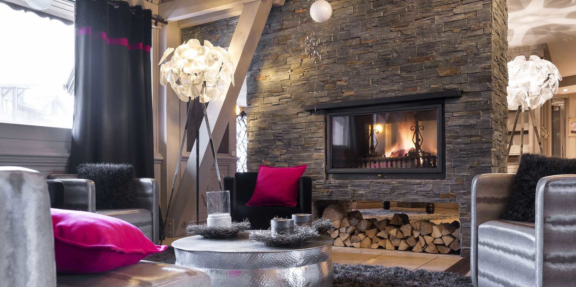 Residences Village Montana Val Thorens Les 3 Vallees Frankrijk wintersport skivakantie luxe lounge open haard fauteuils zwarte roze kussens lampen hout vloerkleed zwart roze gordijnen raam