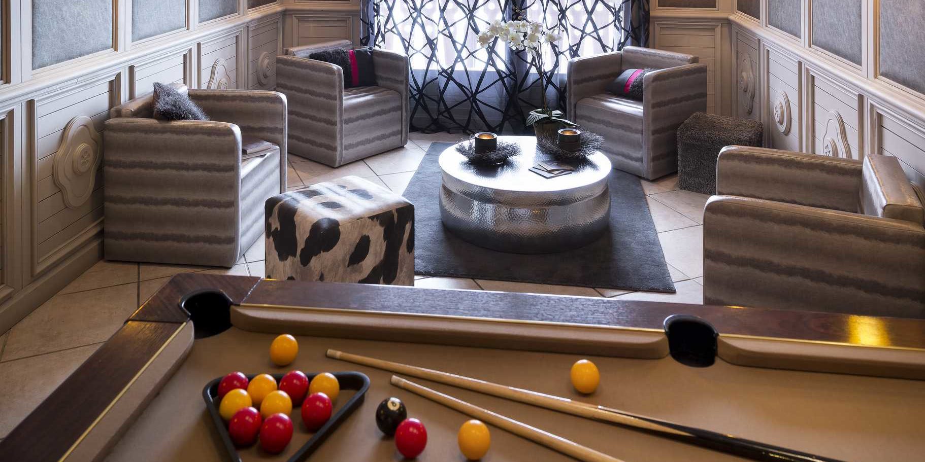 Residences Village Montana Val Thorens Les 3 Vallees Frankrijk wintersport skivakantie luxe lounge pooltafel fauteuils zwart roze kussens salontafel Orchidee kaarsen vloerkleed hocker raam