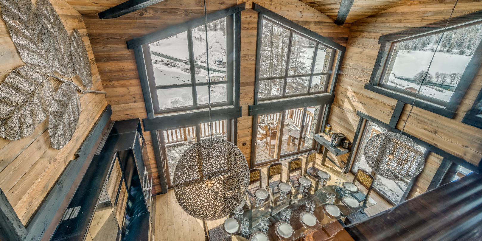 Chalet Ubud Tignes Les Brevieres Tignes-Val d'Isere Frankrijk wintersport skivakantie luxe living eetkamer lampen hoge ramen uitzicht sneeuw bomen blad