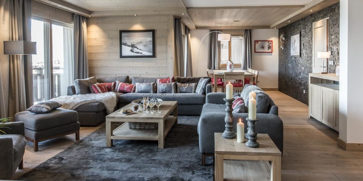 Alpine Residences Courchevel Les 3 Vallees Frankrijk wintersport skivakantie luxe Aspen Lodge living lounge hoekbank fauteuil hocker Champagne glazen hapjes kaarsen vloerkleed schilderij ramen