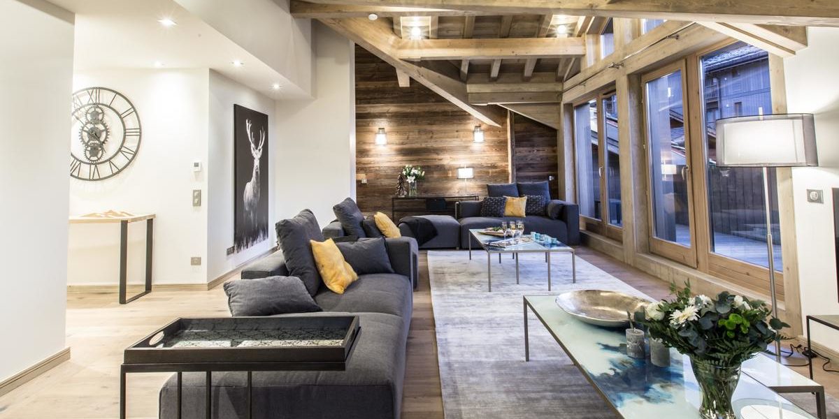 Alpine Residences Courchevel Les 3 Vallees Frankrijk wintersport skivakantie luxe Keystone Lodge living banken salontafel bloemen kaarsen vloerkleed klok schilderij hert ramen houten balken
