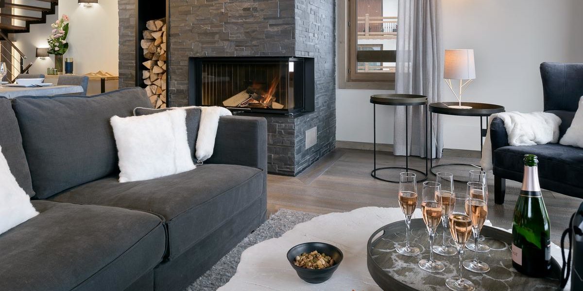 Alpine Residences Courchevel Les 3 Vallees Frankrijk wintersport skivakantie luxe Residence Le C bank Champagne glazen hapjes vloerkleed open haard hout tafeltjes fauteuil raam