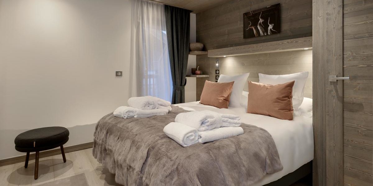 Alpine Residences Courchevel Les 3 Vallees Frankrijk wintersport skivakantie luxe Residence Le C slaapkamer 2-persoonsbed handdoeken hocker schilderij hout verlichting