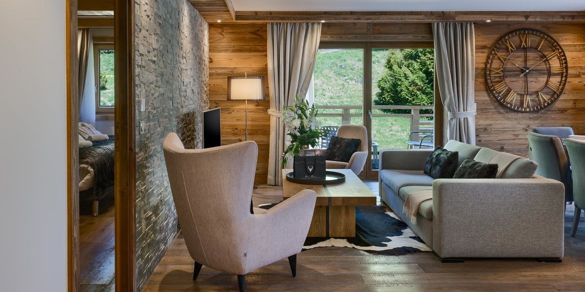 Alpine Residences Les Gets Les Portes du Soleil Frankrijk wintersport skivakantie luxe Annapurna living bank fauteuil plant lamp klok vloerkleed hout raam eetkamerstoelen