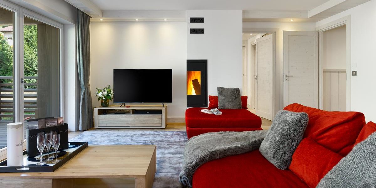 Alpine Residences Les Gets Les Portes du Soleil Frankrijk wintersport skivakantie luxe Annapurna living rode banken kleed vloerkleed Champagneglazen TV houtkachel raam
