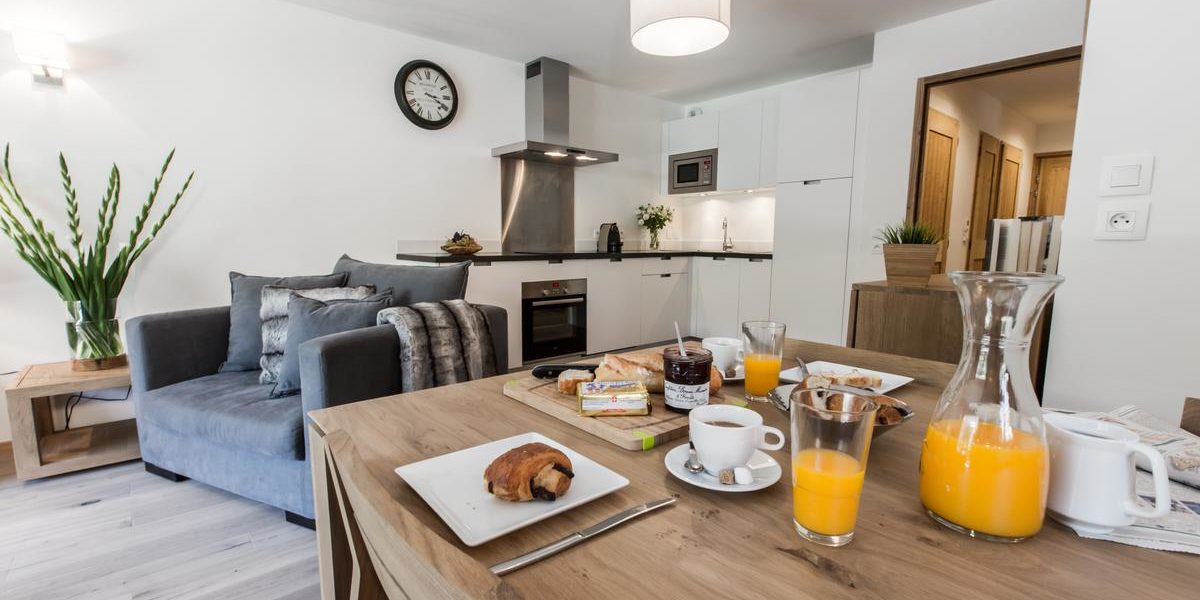 Alpine Residences Les Gets Les Portes du Soleil Frankrijk wintersport skivakantie luxe K2 eetkamer gedekte tafel ontbijt jus d'orange fauteuil keuken plant klok lamp