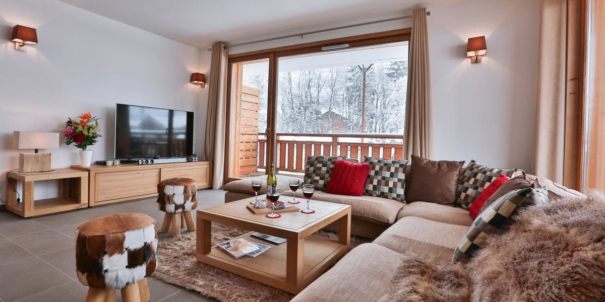 Alpine Residences Les Gets Les Portes du Soleil Frankrijk wintersport skivakantie luxe K2 living lounge hoekbank kussens hocker vloerkleed TV verlichting raam balkon