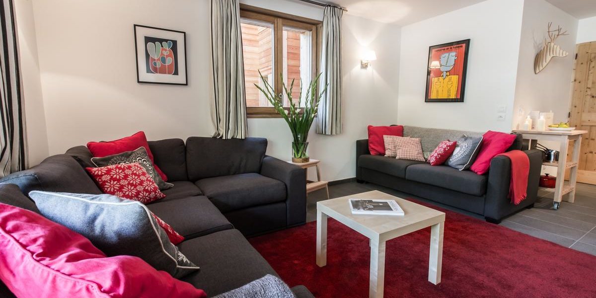 Alpine Residences Les Gets Les Portes du Soleil Frankrijk wintersport skivakantie luxe K2 lounge bank kussens rood vloerkleed schilderijen hert plant raam