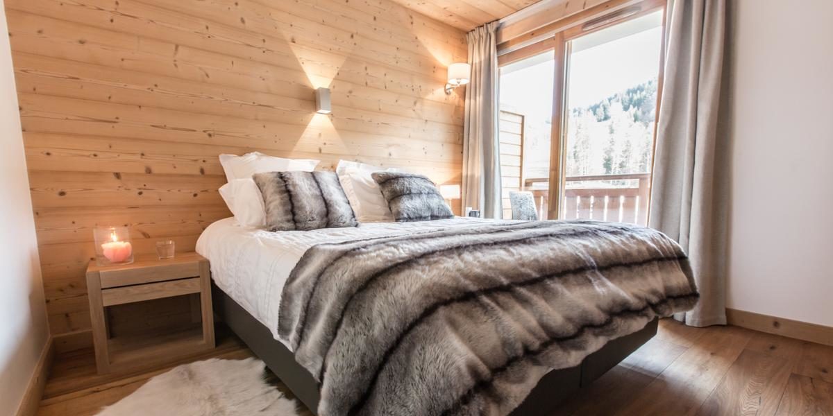 Alpine Residences Les Gets Les Portes du Soleil Frankrijk wintersport skivakantie luxe Kailash slaapkamer 2-persoonsbed hout nachtkastje kaars hoge ramen gordijnen