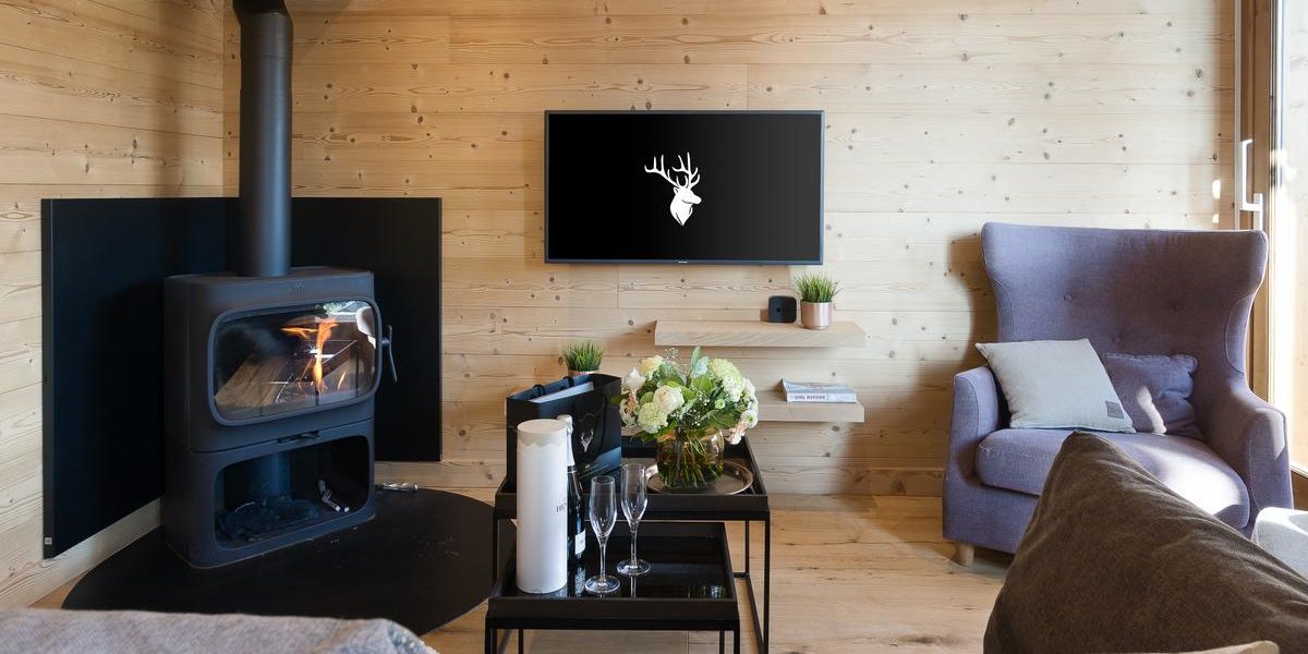 Alpine Residences Les Gets Les Portes du Soleil Frankrijk wintersport skivakantie luxe Kilimandjaro living houtkachel fauteuil salontafel Champagne bloemen TV hout raam