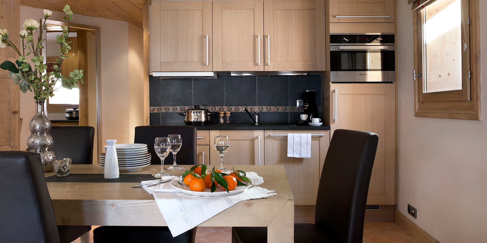 CGH L'Oree des Neiges Vallandry Paradiski Frankrijk wintersport skivakantie luxe gedekte tafel fruit wijnglazen stoelen bloemen houten keuken