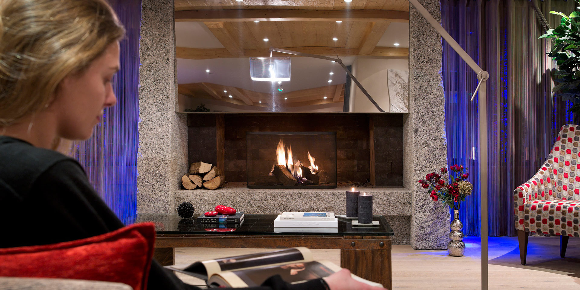 CGH Le Cristal de l'Alpe Alpe d' Huez Grand Domaine Frankrijk wintersport skivakantie luxe receptie dame open haard hout boek kaarsen bloemen fauteuil