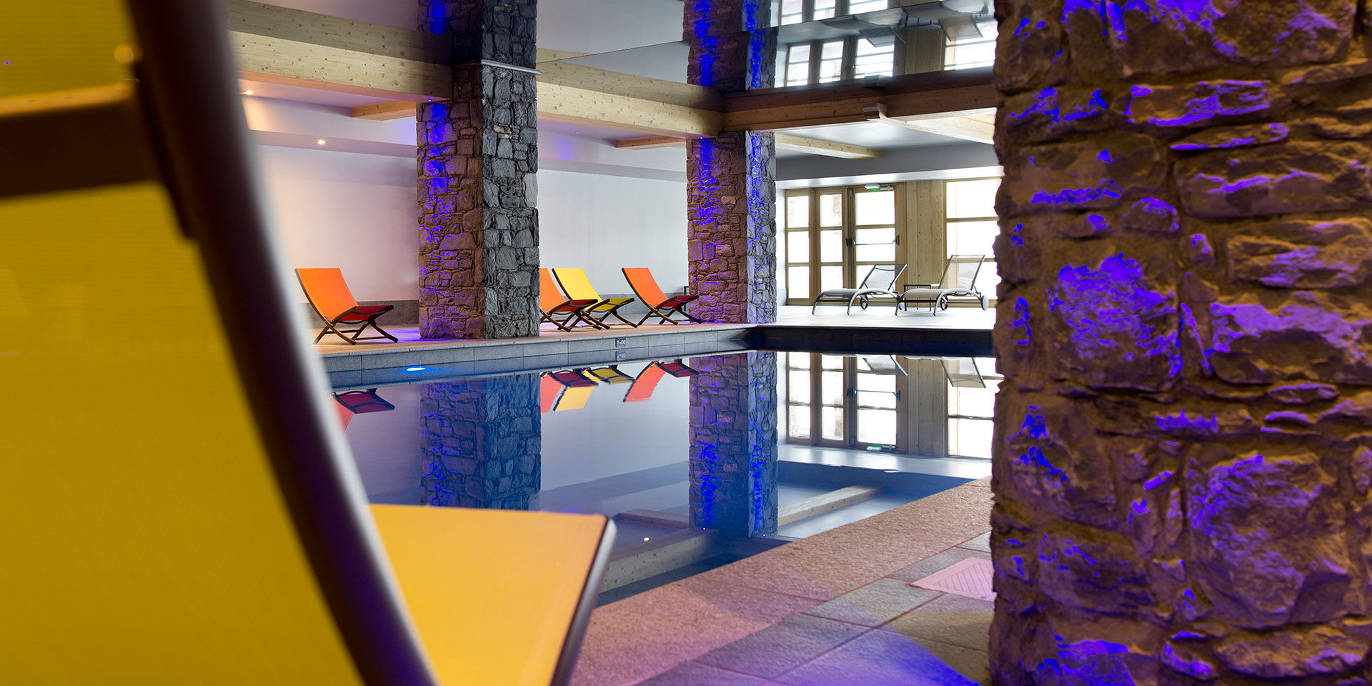 CGH Le Cristal de l'Alpe Alpe d' Huez Grand Domaine Frankrijk wintersport skivakantie luxe zwembad ligstoelen stenen pilaar ontspannen relaxen genieten