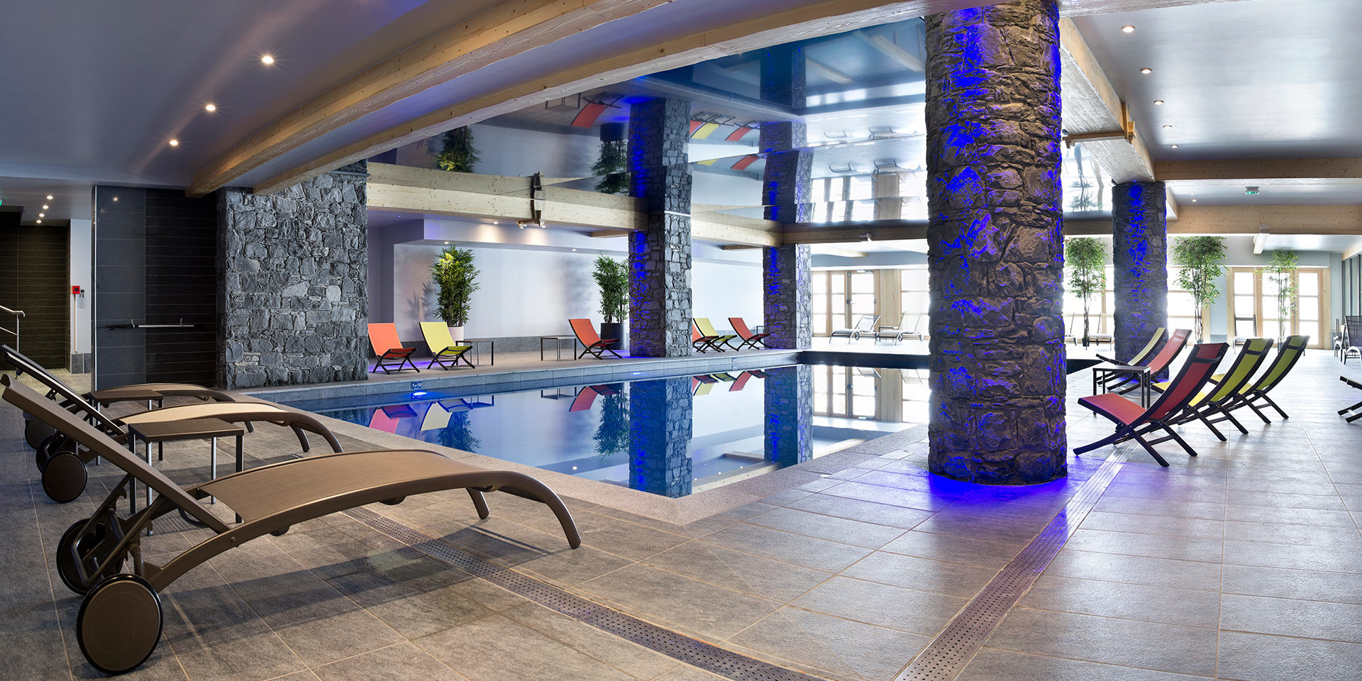 CGH Le Cristal de l'Alpe Alpe d' Huez Grand Domaine Frankrijk wintersport skivakantie luxe zwembad ligstoelen stenen pilaar ramen ontspannen relaxen genieten