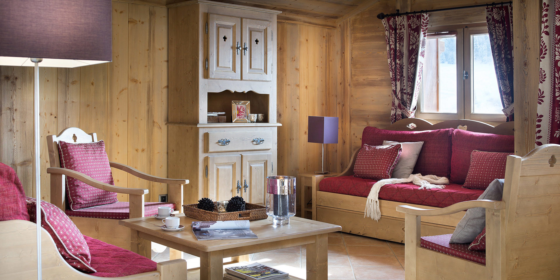 CGH Le Hameau de Pierre Blanche Les Houches Chamonix Mont Blanc Frankrijk wintersport skivakantie luxe zithoek rode banken fauteuils salontafel hout raam