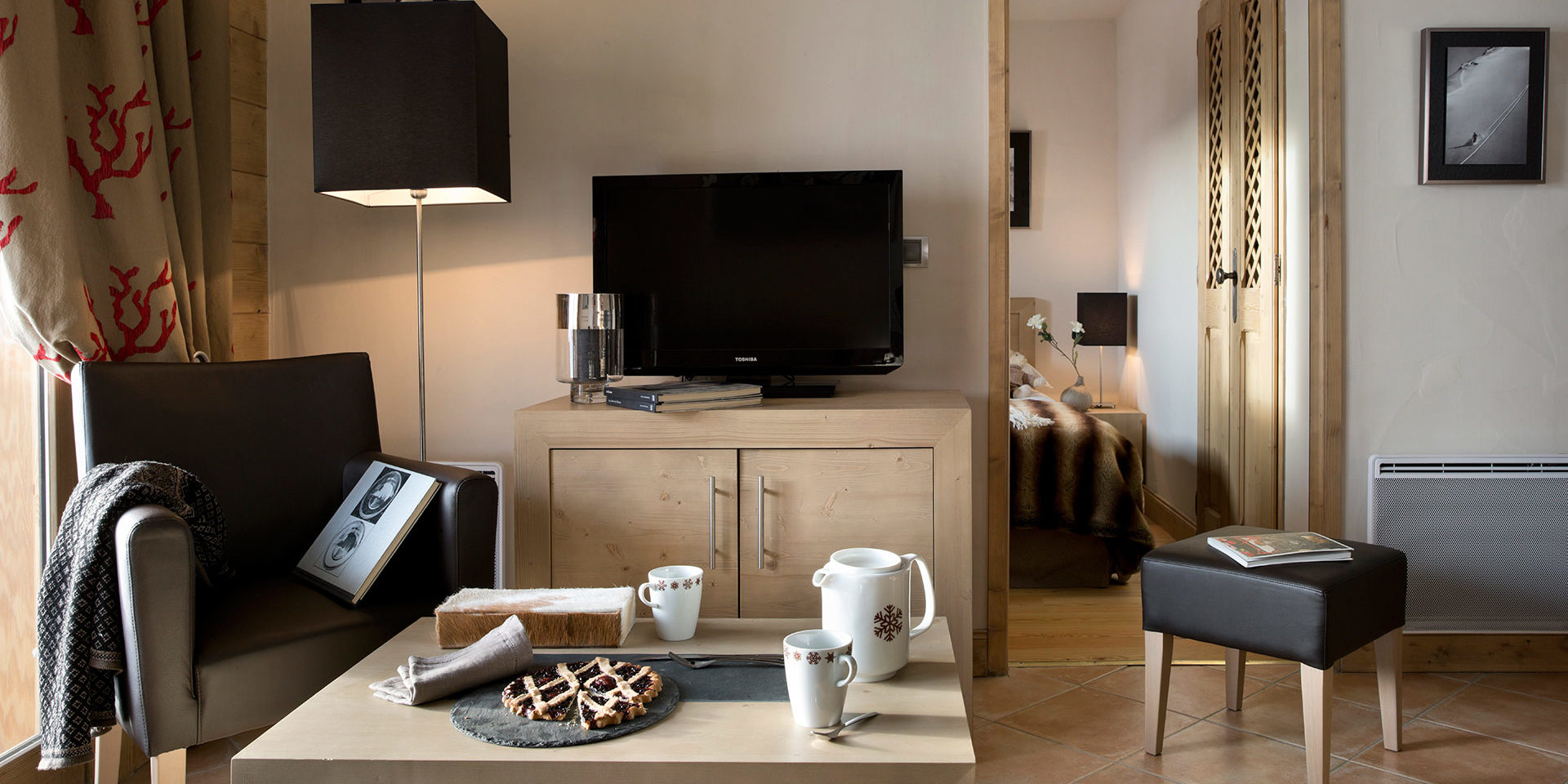 CGH Le Jhana Tignes Tignes-Val d'Isere Frankrijk wintersport skivakantie luxe fauteuil high tea taart lamp TV hocker boek slaapkamer