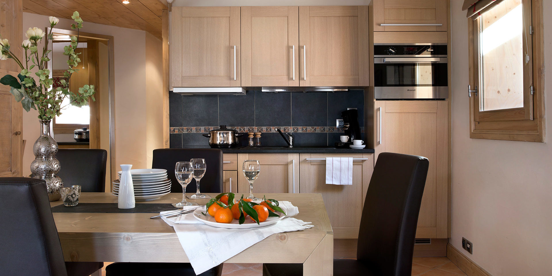 CGH Le Jhana Tignes Tignes-Val d'Isere Frankrijk wintersport skivakantie luxe gedekte tafel fruit wijnglazen bloem keuken hout raam