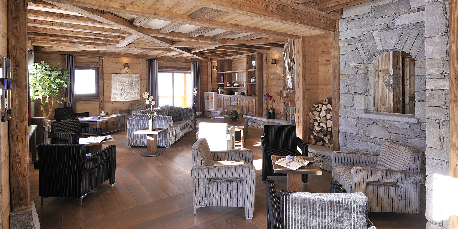 CGH Le Jhana Tignes Tignes-Val d'Isere Frankrijk wintersport skivakantie luxe receptie fauteuils bank Orchidee plant hout ramen houten balken