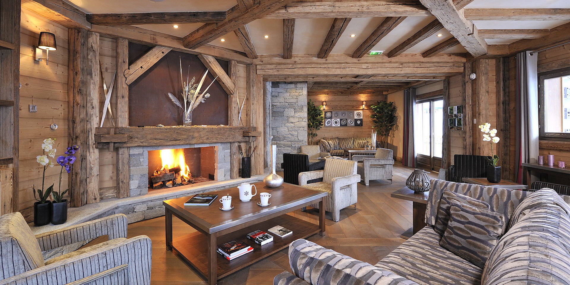 CGH Le Jhana Tignes Tignes-Val d'Isere Frankrijk wintersport skivakantie luxe receptie open haard Orchidee fauteuils bank high tea houten balken plant ramen