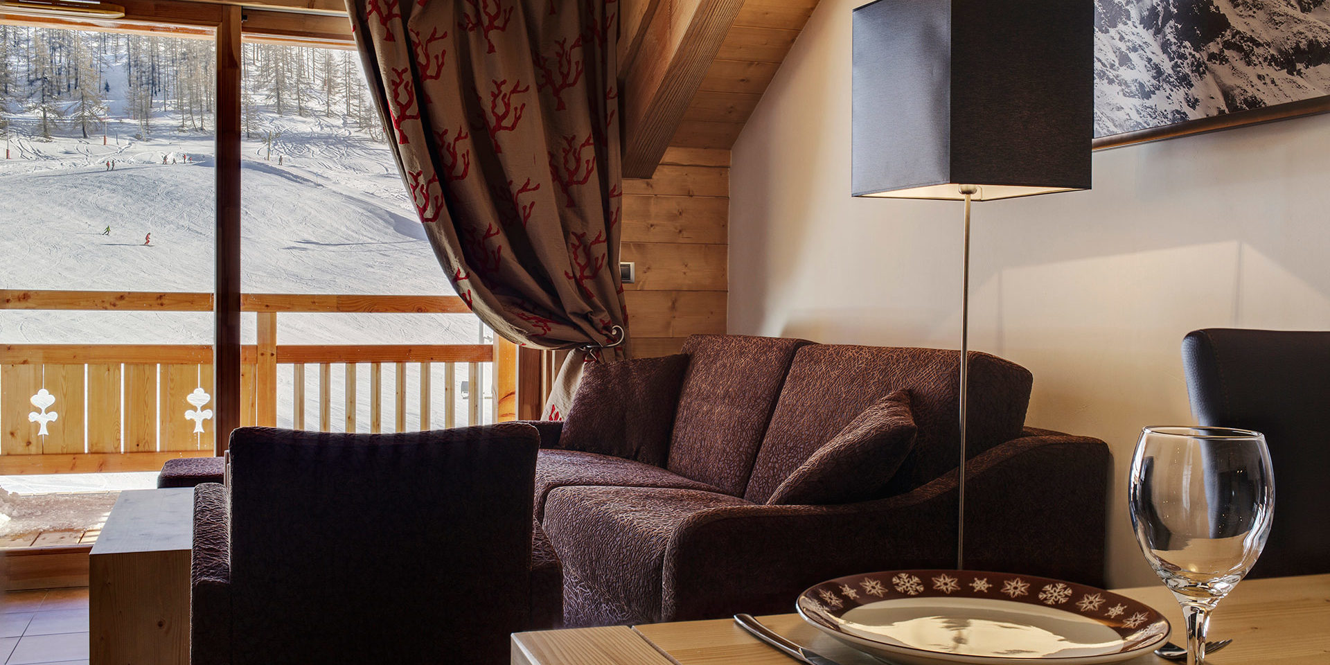CGH Le Napoleon Montgenevre Via Lattea Frankrijk wintersport skivakantie luxe zithoek bank fauteuil gordijnen balkon piste bomen skiers sneeuw