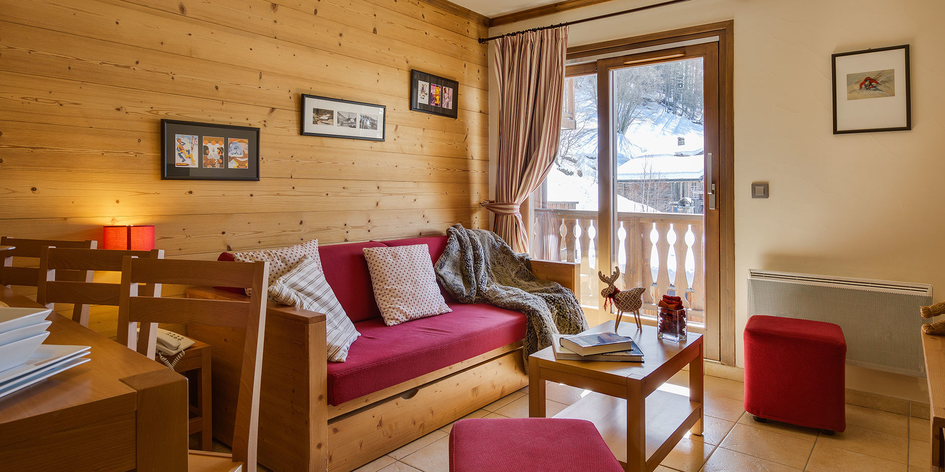 CGH Le Ruitor Sainte Foy Sainte Foy Tarentaise Frankrijk wintersport skivakantie luxe rode bank eettafel stoelen schilderijen rode hockers eland balkon bomen sneeuw