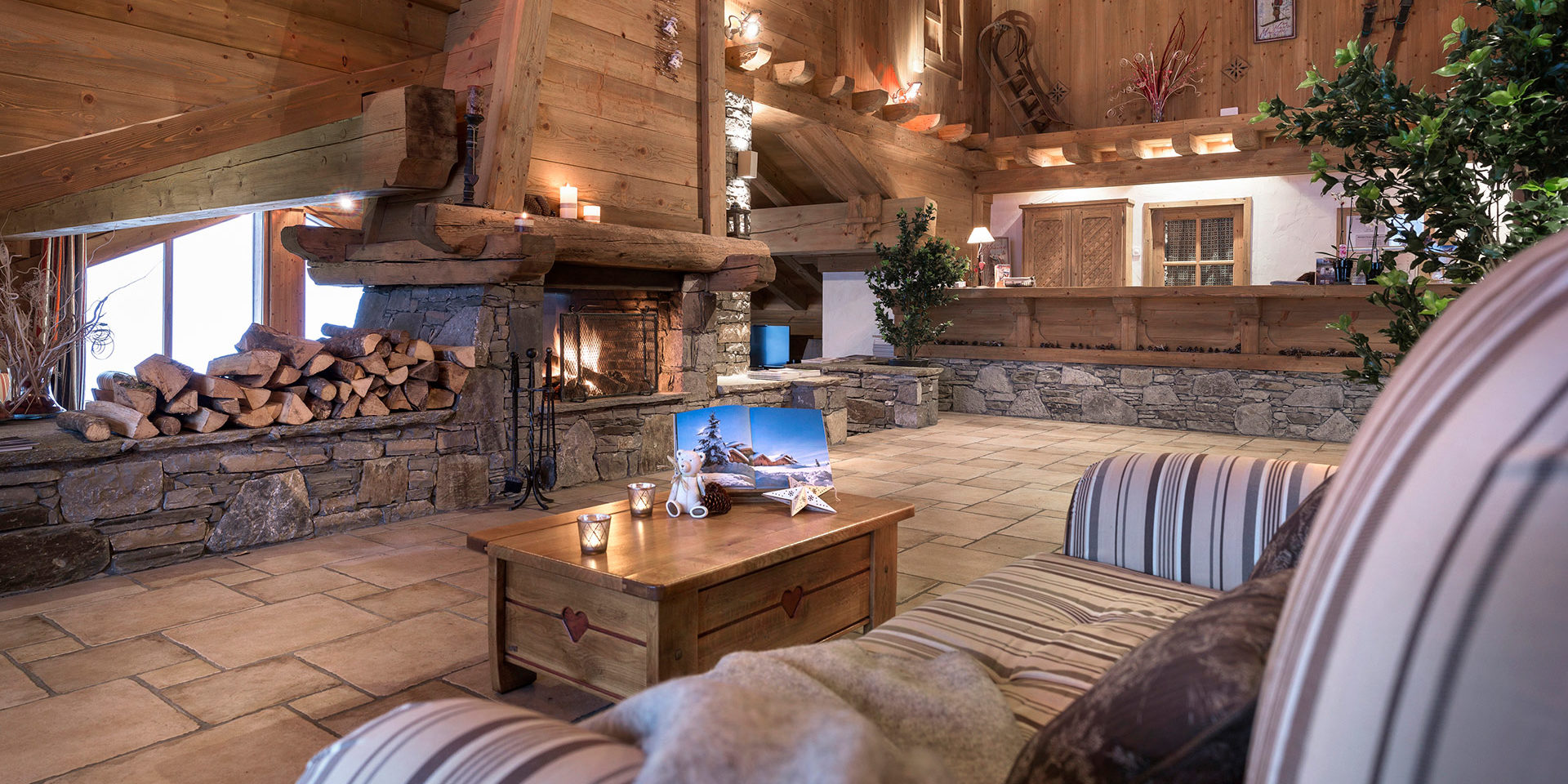 CGH Les Alpages de Champagny Champagny en Vanoise Paradiski Frankrijk wintersport skivakantie luxe receptie open haard fauteuil beertje kaarsen hout houten balken slee plant