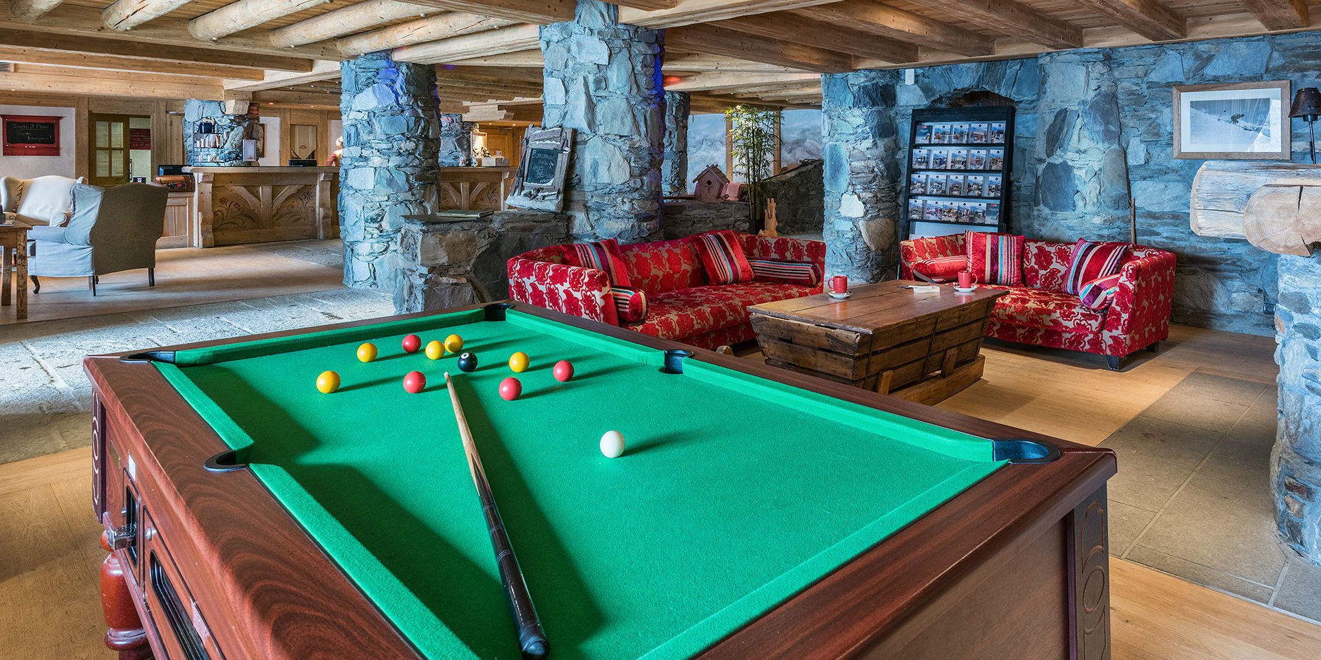 CGH Les Cimes Blanches La Rosiere Espace San Bernardo Frankrijk wintersport skivakantie luxe receptie biljard rode banken stenen pilaren fauteuils houten balken