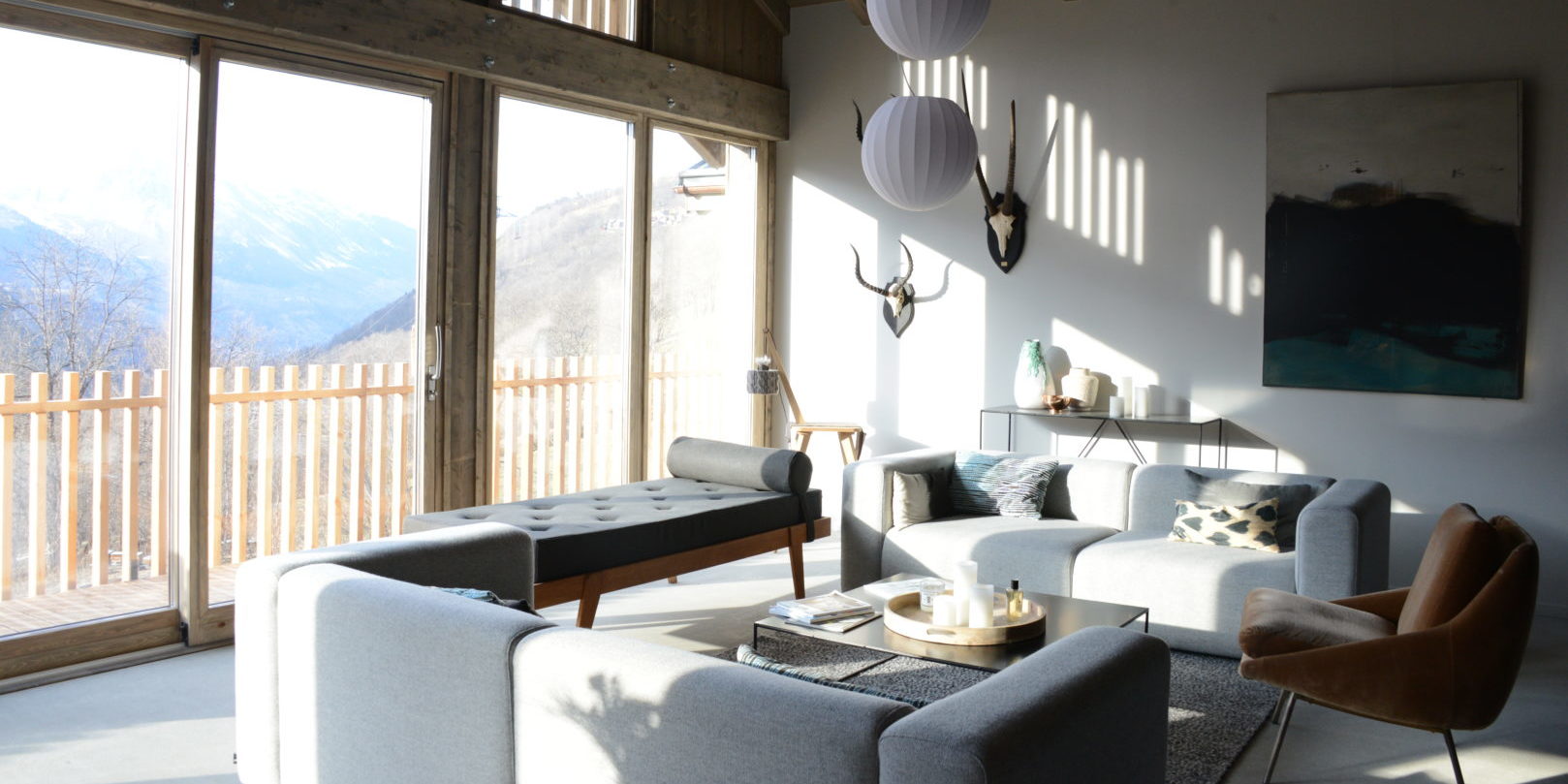 Chalet by U no. 2 Saint Martin de Belleville Les 3 Vallees Frankrijk wintersport skivakantie luxe living bank chaise longue fauteuil vloerkleed schilderij gewei hanglampen hoge ramen