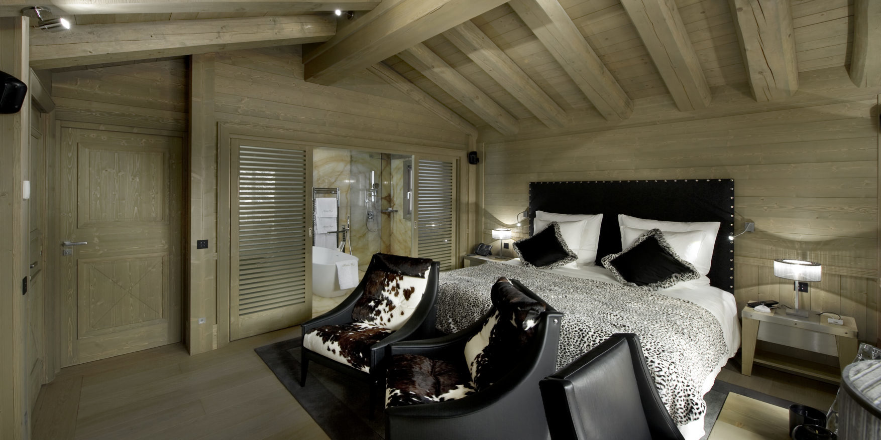 Le K2 Palace Suite-Chalet Hidden Peak Courchevel Les 3 Vallees Frankrijk wintersport skivakantie luxe slaapkamer 2-persoonsbed zwart hoofdbord fauteuils bureau badkamer bad houten balken