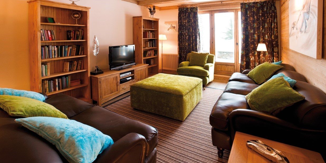 Appartement Petit Choucas Val d'Isere Tignes & Val d'Isere Frankrijk wintersport skivakantie luxe leren banken kussens hocker TV houten kasten boeken raam hout