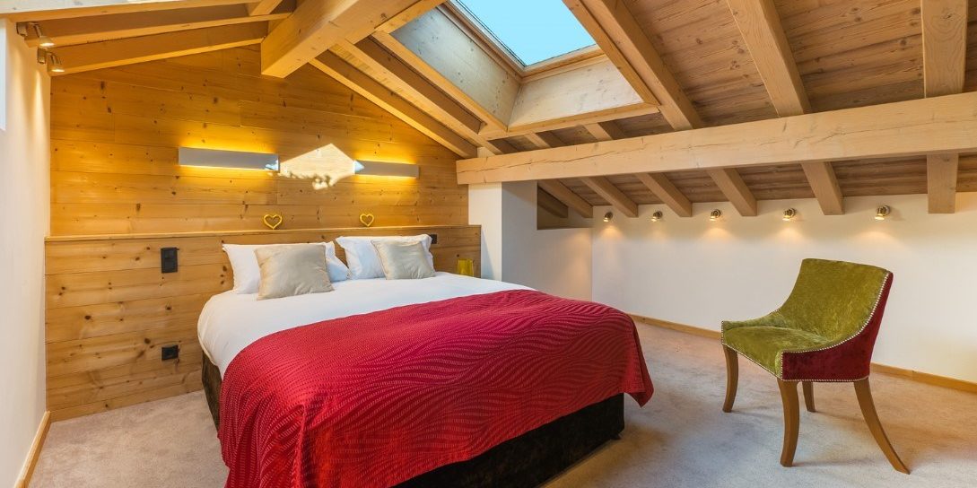 Chalet Alaska Morzine Les Portes du Soleil Frankrijk wintersport skivakantie luxe slaapkamer 2-persoonsbed bedsprei fauteuil dakramen houten balken