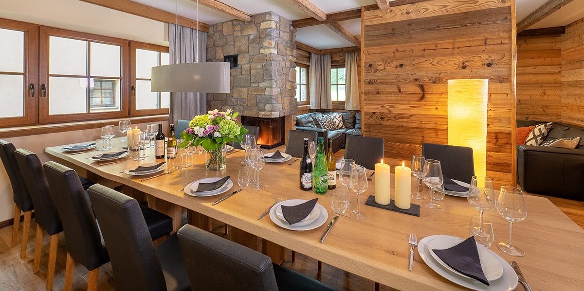 Chalet Cristal Sankt Anton Arlberg Oostenrijk wintersport skivakantie luxe eetkamer gedekte tafel kaarsen bloemen wijnglazen houten balken hout ramen