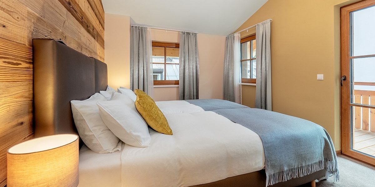 Chalet Cristal Sankt Anton Arlberg Oostenrijk wintersport skivakantie luxe slaapkamer 2 aparte bedden hoofdbord kussens lamp ramen deur balkon hout