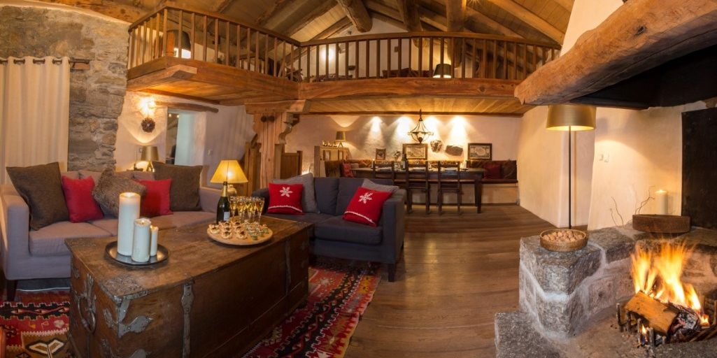 Chalet La Petite Ferme Val d'Isere Tignes & Val d'Isere Frankrijk wintersport skivakantie luxe living open haard hoekbank kaarsen vloerkleed Champagne canapes hout